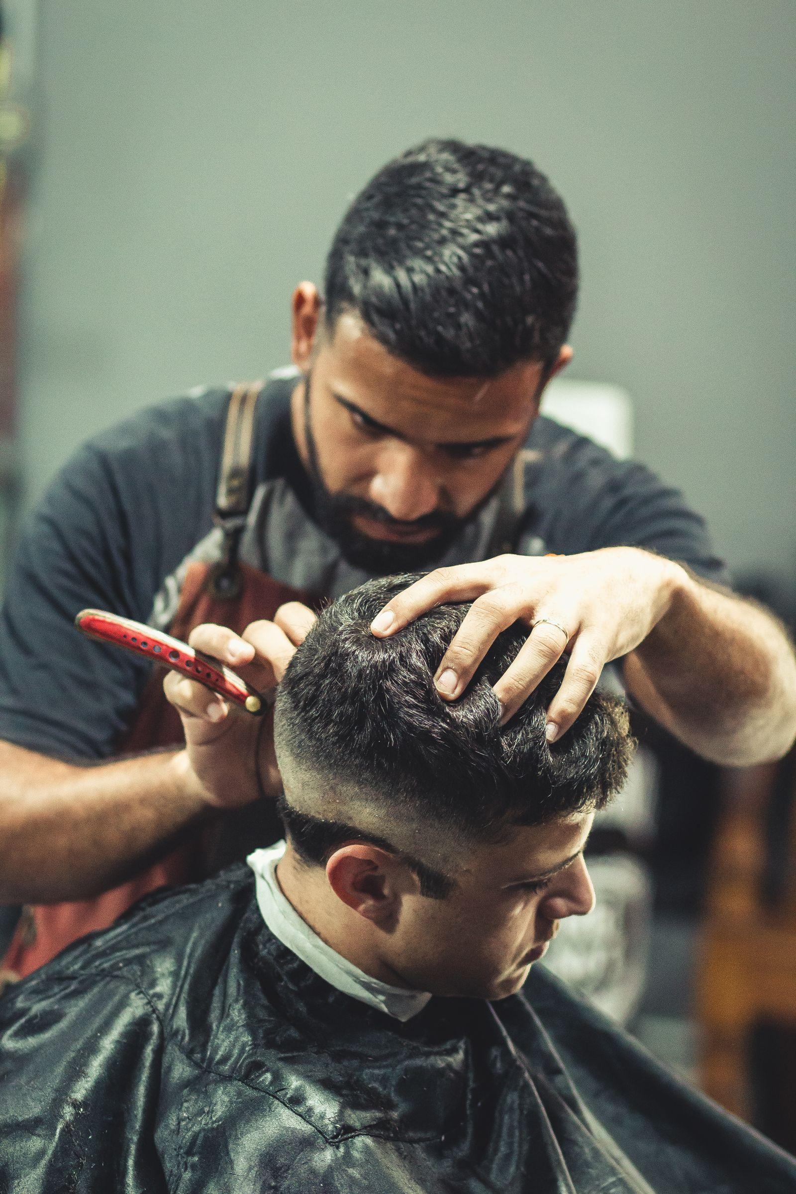 Barber using a straight razor to detail the back of a client's fade