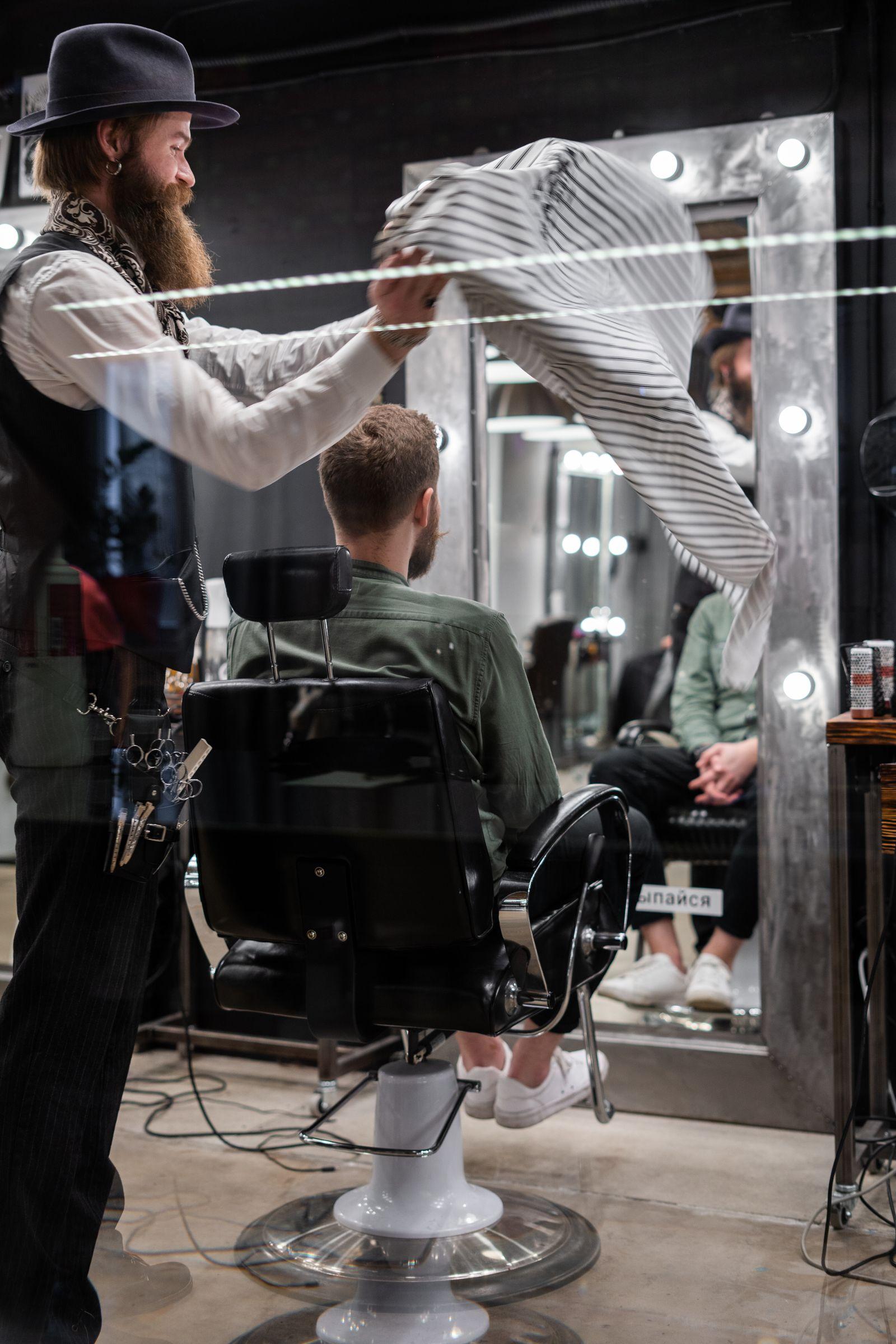 A barber chair in front of a lit mirror in a dark studio