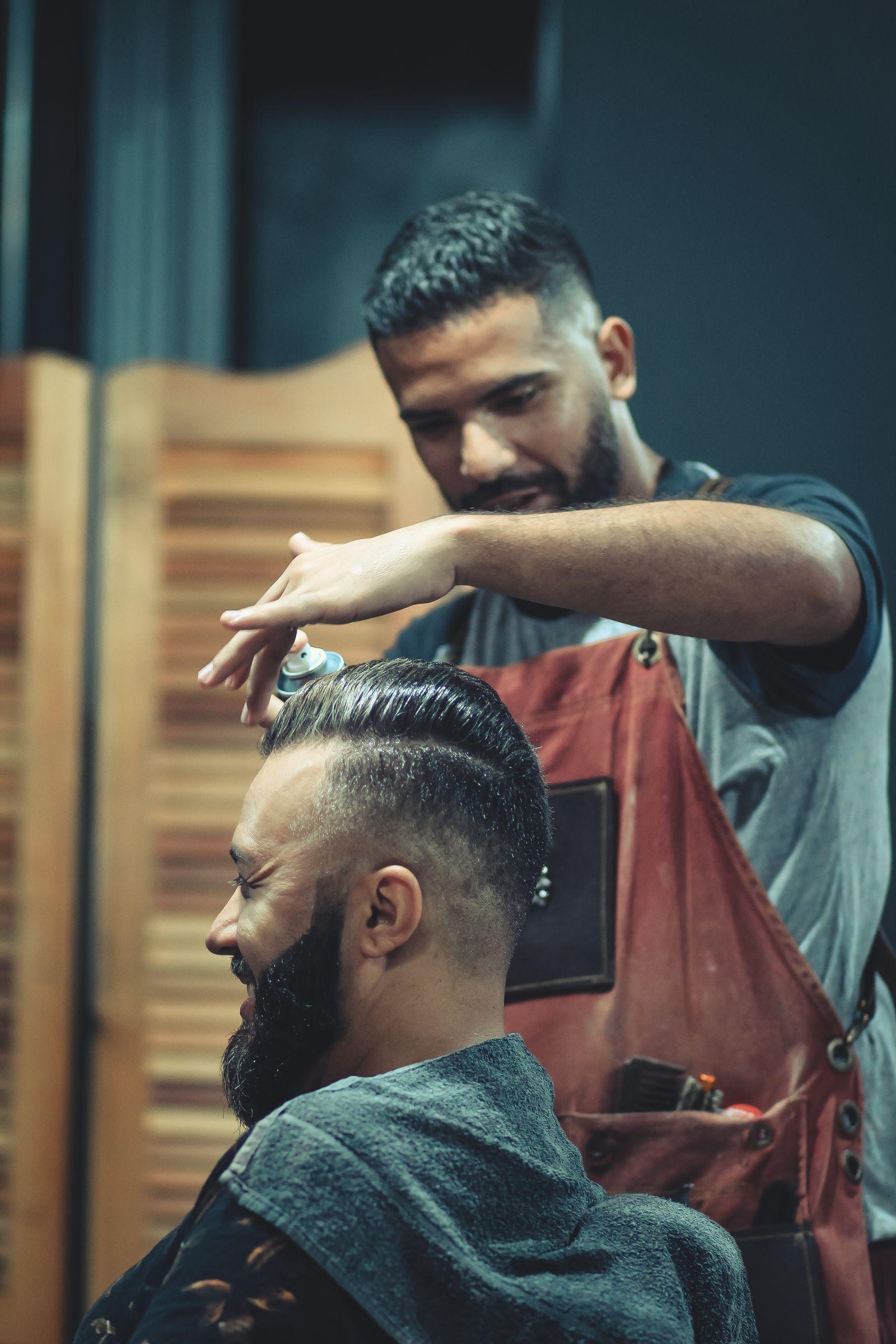 Barber finishing a client's side-parted cut and full beard