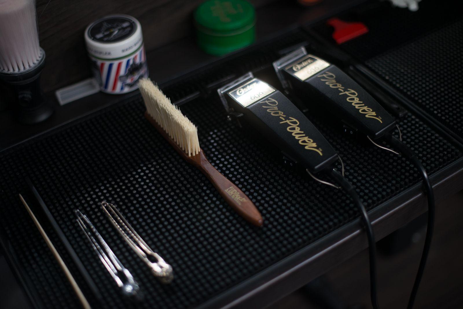 Clippers, a fade brush and clips arranged on a barber's station